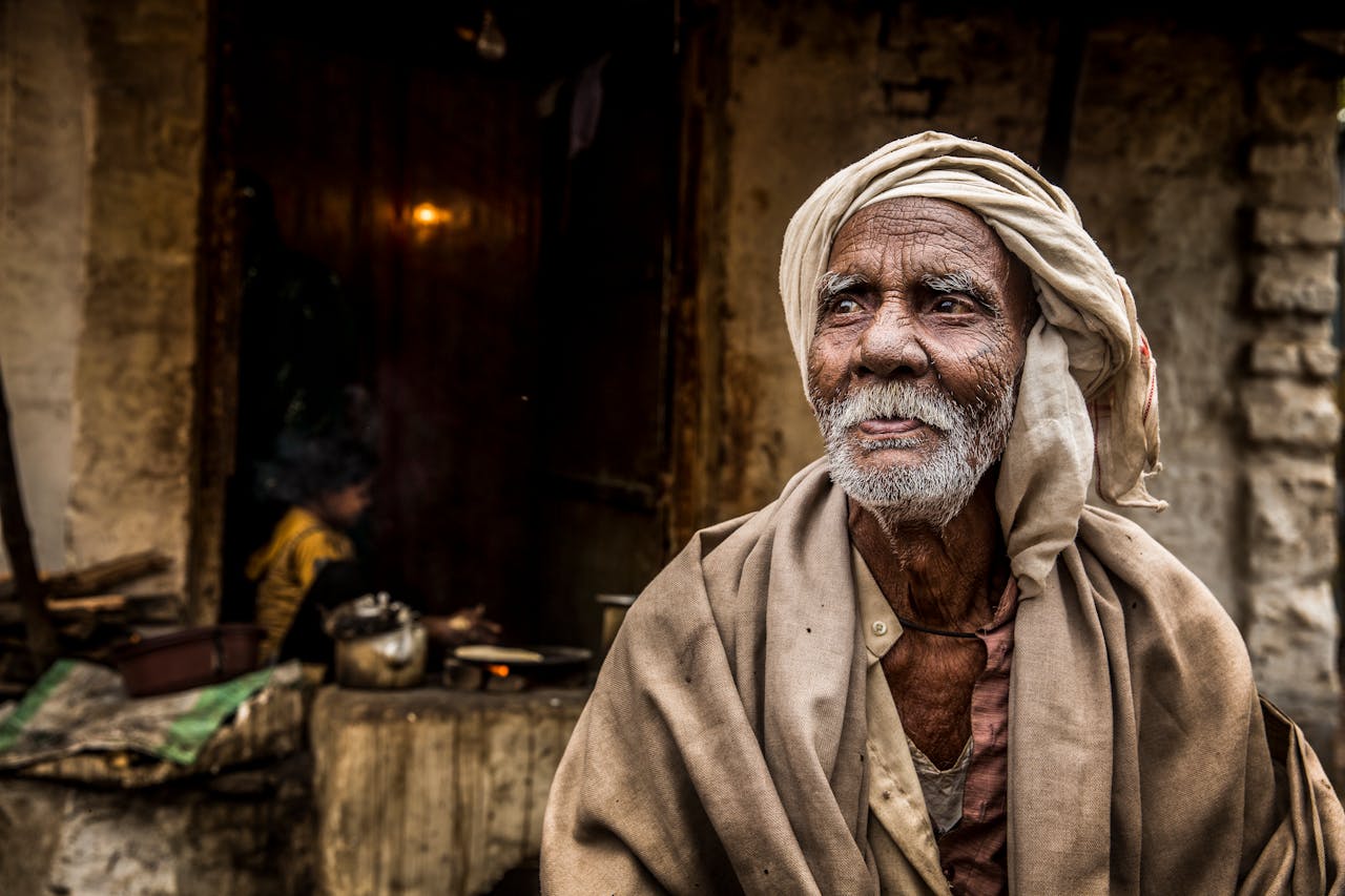 services-02 Close-up portrait of an elderly man with a headscarf, deeply expressive face, and traditional attire.